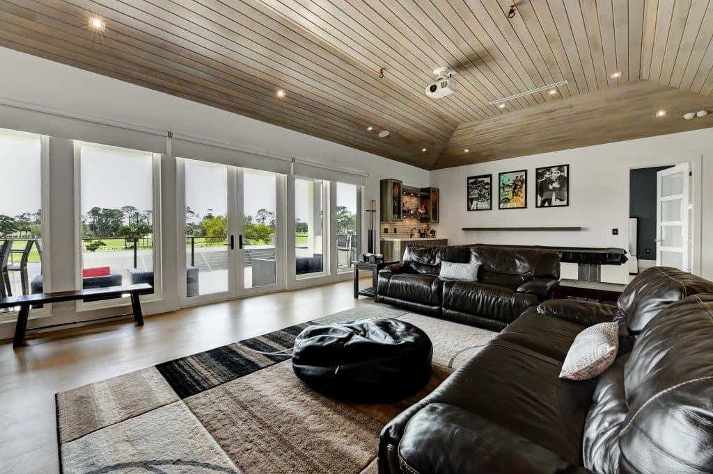 Patel living room with large leather couches facing a golf course designed & constructed by Rita Jones Construction in Panama City Beach Florida